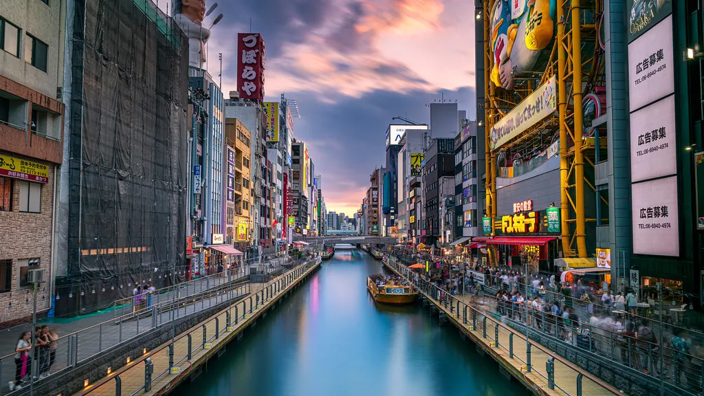 Dotonbori canal in Osaka at dusk, lined with lit shop signs and walkways